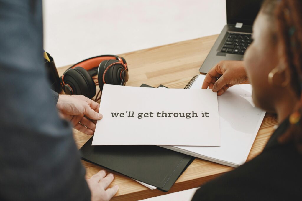 Hands holding a motivational note at a desk, symbolizing support and hope.